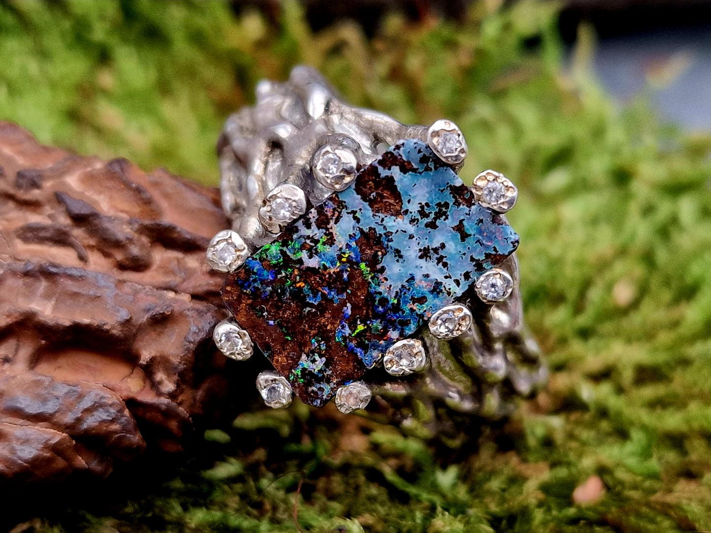 Boulder Opal Design Ring aus 925er Silber, Gr.62 (19,7), massiv, mit 11 facettierten Bergkristallen in den Stotzen der Fassung, wie organisch gewachsen, mehrfarbiges Opalfeuer, Unikat, Handarbeit