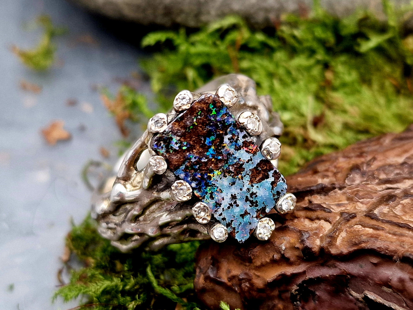 Boulder Opal Design Ring aus 925er Silber, Gr.62 (19,7), massiv, mit 11 facettierten Bergkristallen in den Stotzen der Fassung, wie organisch gewachsen, mehrfarbiges Opalfeuer, Unikat, Handarbeit