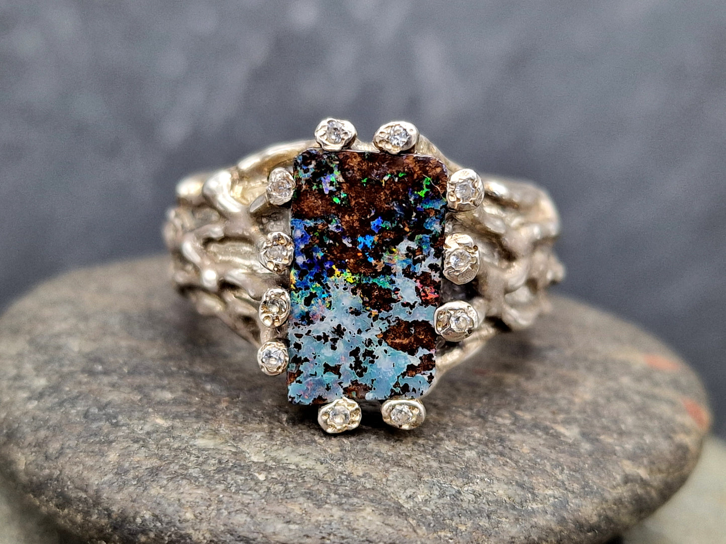 Boulder Opal Design Ring aus 925er Silber, Gr.62 (19,7), massiv, mit 11 facettierten Bergkristallen in den Stotzen der Fassung, wie organisch gewachsen, mehrfarbiges Opalfeuer, Unikat, Handarbeit