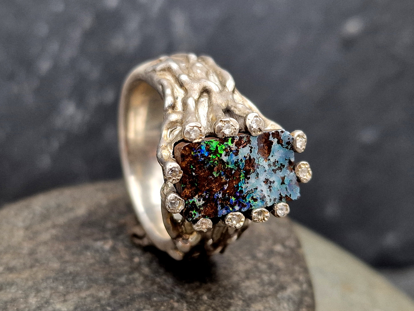 Boulder Opal Design Ring aus 925er Silber, Gr.62 (19,7), massiv, mit 11 facettierten Bergkristallen in den Stotzen der Fassung, wie organisch gewachsen, mehrfarbiges Opalfeuer, Unikat, Handarbeit